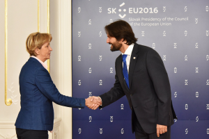 Bundeskanzlerin Angela Merkel und Bundespräsident Joachim Gauck schütteln Hände vor einer Wand mit einem "EU-Gipfel"-Banner und einer Tür im Hintergrund, beide lächeln.