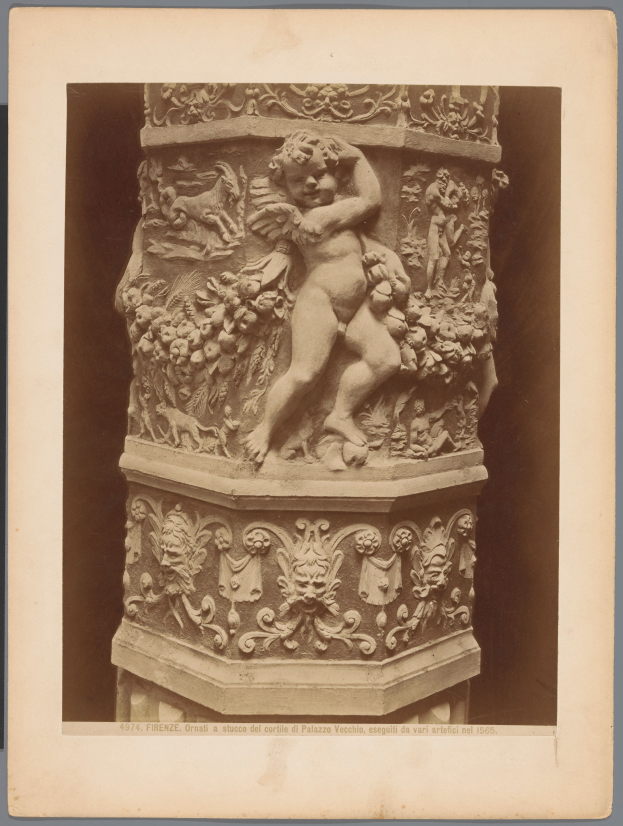 Eine schwarze und weiße Statue eines Cherubs auf einem Sockel, mit dem Cherub in einer anmutigen Pose, ausgebreiteten Armen, geneigtem Kopf und geschlossenen Augen, während der Sockel detailreiche Verzierungen aufweist.
