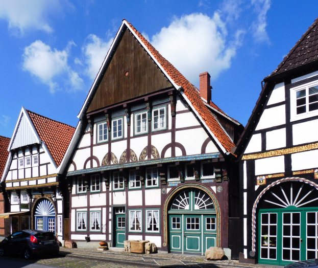Reihe von Fachwerkhäusern in der Altstadt von Heidelberg mit Fahrzeugen auf der Straße und einem bewölkten Himmel.
