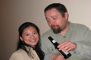 Mann mit Flasche starrt lächelnde Frau an einer Wand an