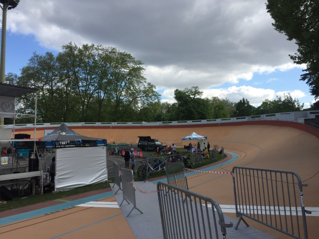 Eine Gruppe von Radfahrern auf einer Schmutzstrecke bei den UCI BMX-Weltmeisterschaften 2018, mit Zuschauern, Zelten und Fahrzeugen im Hintergrund.