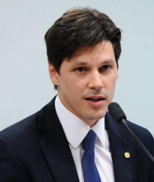 Ein Mann im Anzug und Krawatte spricht vor einer Wand in ein Mikrofon und scheint eine Erklärung abzugeben.