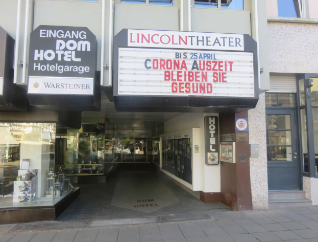 Außenansicht des Lincoln Theaters in Berlin, Deutschland, mit Glasfenstern und -türen sowie einer Tafel mit Text und einem Inneren voller verschiedener Gegenstände.