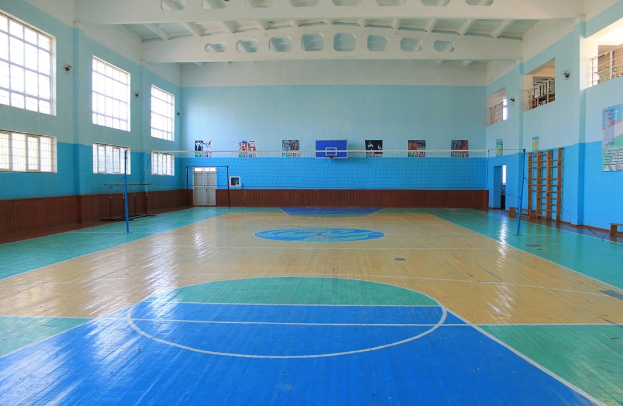 Großes Gymnastik mit blauem und weißem Boden, Basketballfeld, Netz, Stangen, Tür, Fenster, Wandplakate, Geländer und Dach.