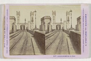 Schwarz-weißes stereoskopisches Foto einer Eisenbahnbrücke in Köln, Deutschland, das Eisenbahninfrastruktur, Umgebungswände, Pfosten, Statuen, Himmel und Text zeigt.