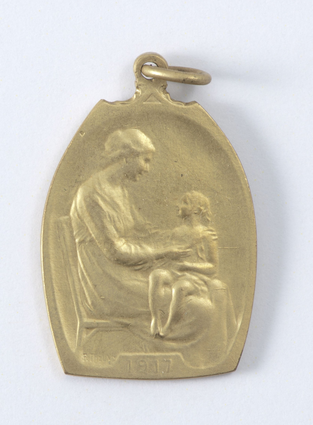 Goldmedaille mit Relief einer Frau in weißem Kleid mit Haarknoten, die ein Kind hält, das zu ihr aufschaut, beschriftet mit "Mutter und Kind."