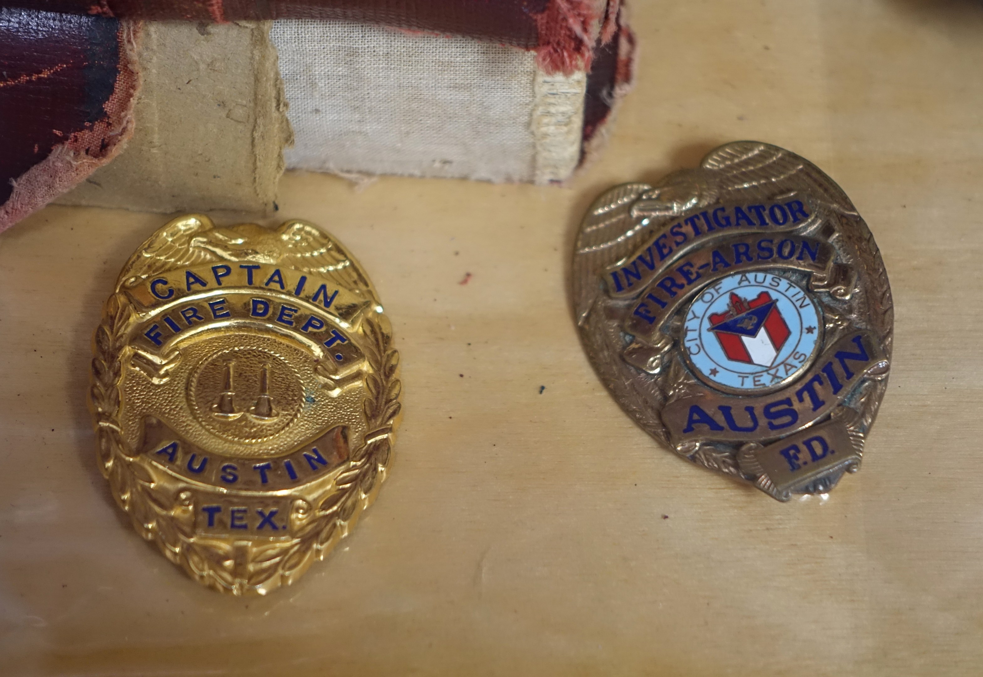 Zwei Polizeimarke mit Text darauf auf einem Holztisch mit einem Tuch oben.