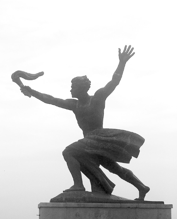 Eine Statue mit einem bewölkten Himmel im Hintergrund.
