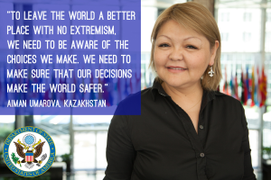 Eine Frau in einem schwarzen Kleid steht vor einem Fenster mit einer Aussage über die Weltverbesserung, mit sichtbaren Flaggen im Hintergrund.