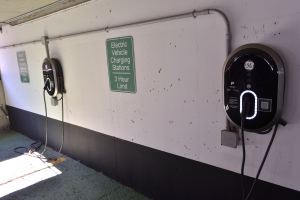 Eine Ladesäule für Elektrofahrzeuge in einer Tiefgarage mit zwei an der Wand angebrachten Ladesäulen und Tafeln mit Text darauf, der Boden ist unten im Bild sichtbar.