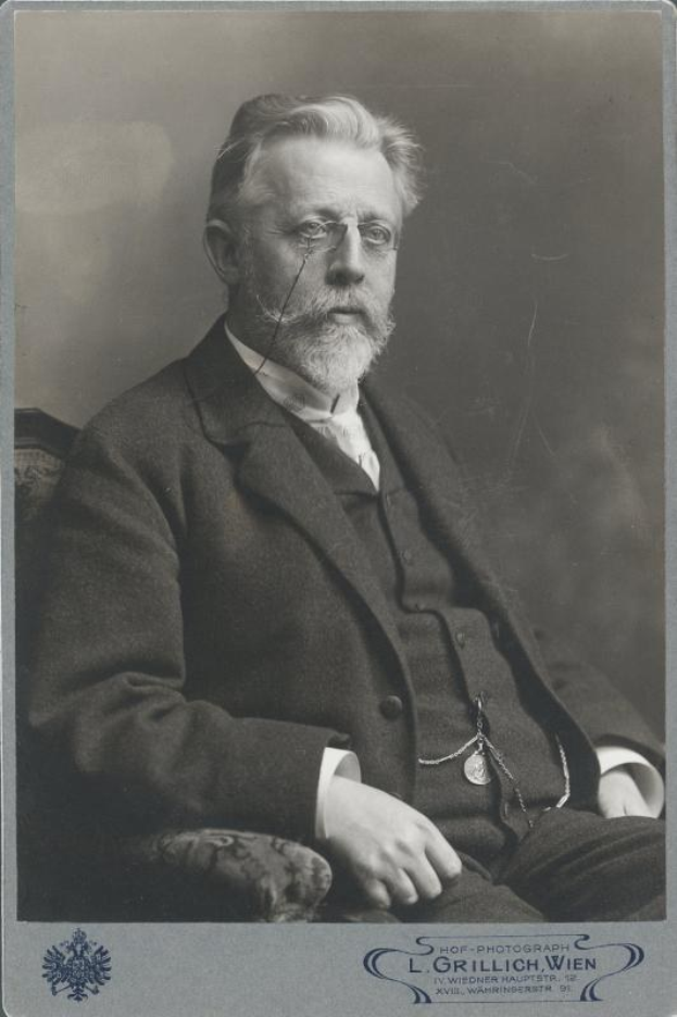 Schwarz-weiß-Fotografie eines bärtigen Mannes mit Brille, der in einem Stuhl sitzt, mit Text unten: "L. Grillich Wien, der Gründer der deutschen Revolution"