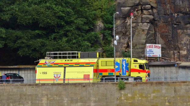 Ambulanz am Straßenrand neben einer Klippe mit Bäumen und einem Auto im Hintergrund geparkt.