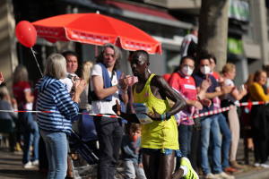 Mann in gelbem T-Shirt läuft durch eine Zuschauermenge bei einem Marathon, umgeben von jubelnden Menschen.