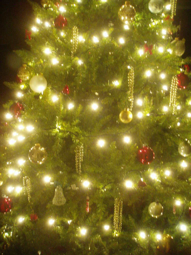 Ein mit Lichtern, Kugeln und diversen Dekorationen geschmückter Weihnachtsbaum.