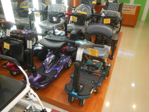 Eine Ausstellung von E-Scootern in einem Geschäft, jedes mit einem Preisschild, mit einem Holztisch und einer Tafel im Hintergrund.