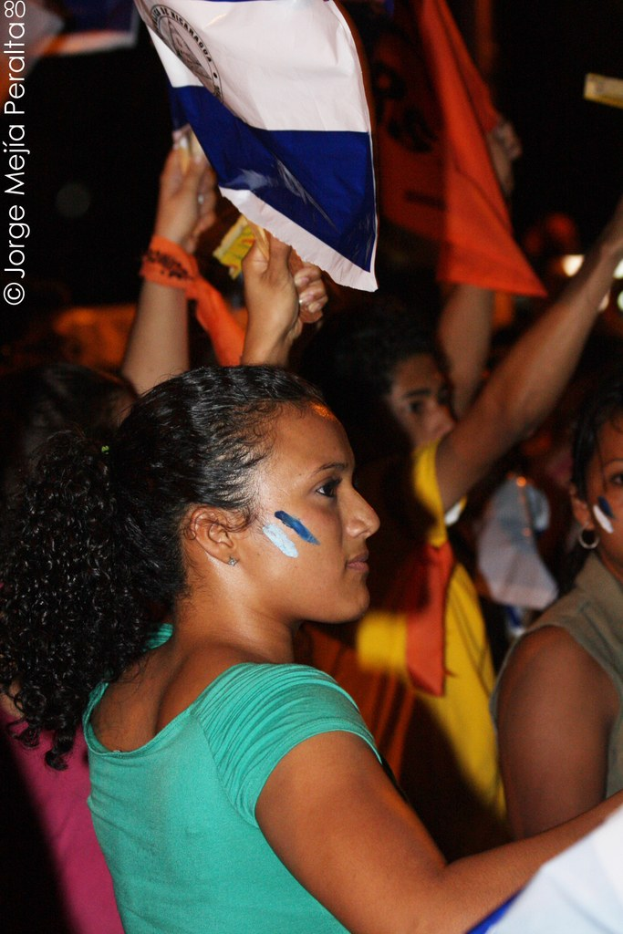 Frauen in grünen T-Shirts mit weißen Abdeckungen bei einer Demonstration, mit mehreren anderen Mädchen dahinter.