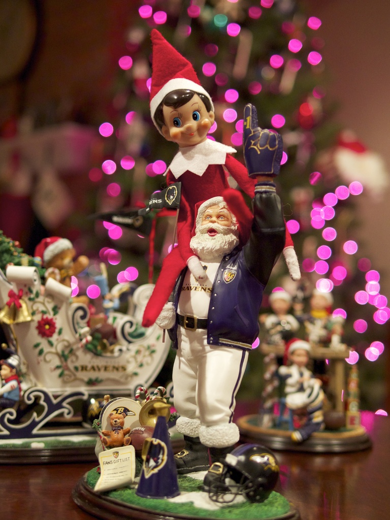 Spielfiguren im Vordergrund mit einem beleuchteten Weihnachtsbaum im Hintergrund.