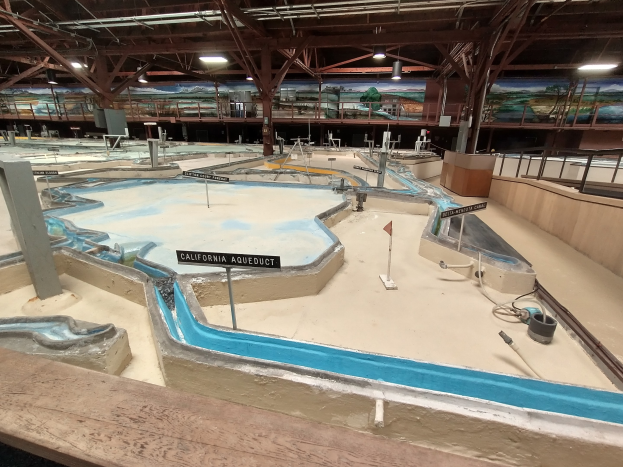 Indoor-Spielplatz mit mehreren Wasserrutschen, Deckenleuchten, Wandgemälden und einem Minigolfplatz.