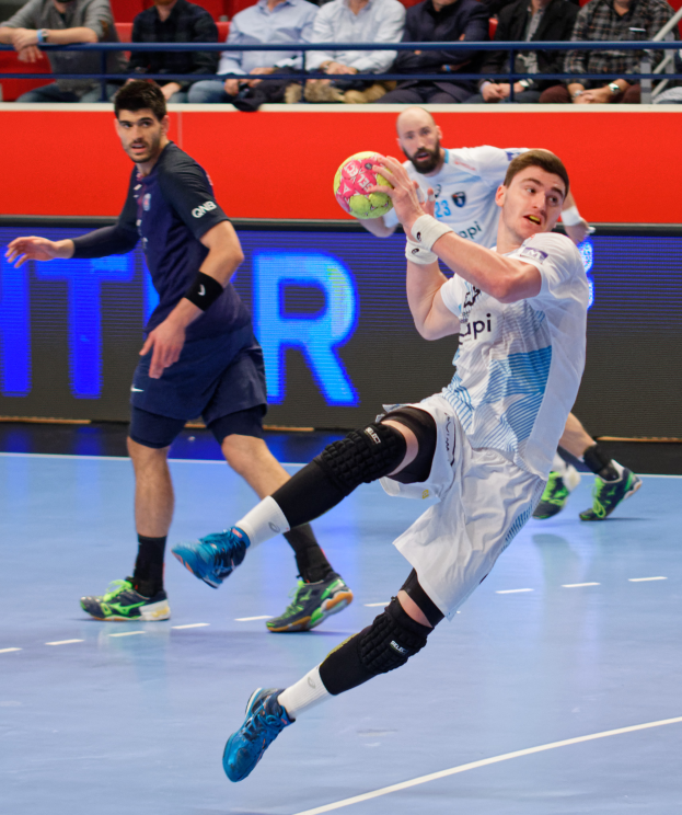 Eine Gruppe von Männern spielt Handball auf einem Platz mit einem Ball in der Mitte, Zuschauer im Hintergrund und eine Tafel mit "Futsal-Weltmeisterschaft 2019" und den Tagen des Ereignisses.