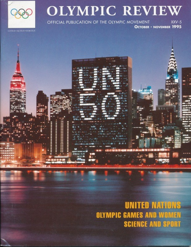 Buch mit dem Titel "Olympische Überprüfung Offizielle Veröffentlichung der Olympischen Bewegung" mit einer Stadtansicht auf dem Cover, das auf einer flachen Oberfläche liegt.