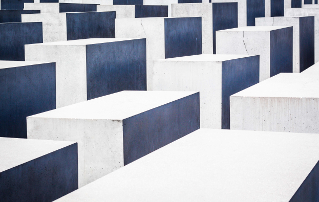 Ein großes Feld von rechteckigen Betonplatten in verschiedenen Höhen, die in einem Gittermuster angeordnet sind, unter einem grauen Himmel.