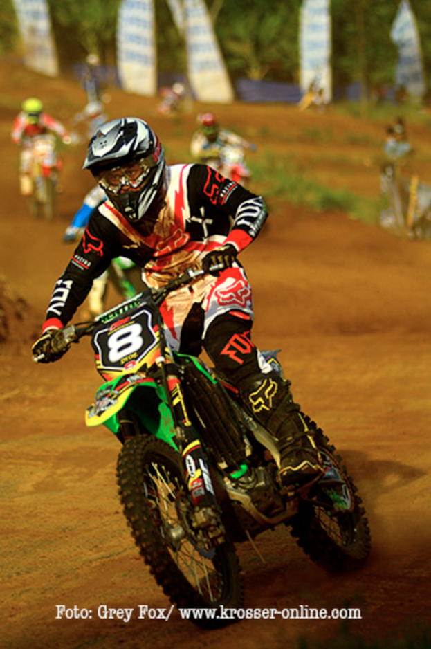 Mehrere Motorradrennfahrer tragen Helme bei einem Rennen, mit Text am unteren Bildrand.