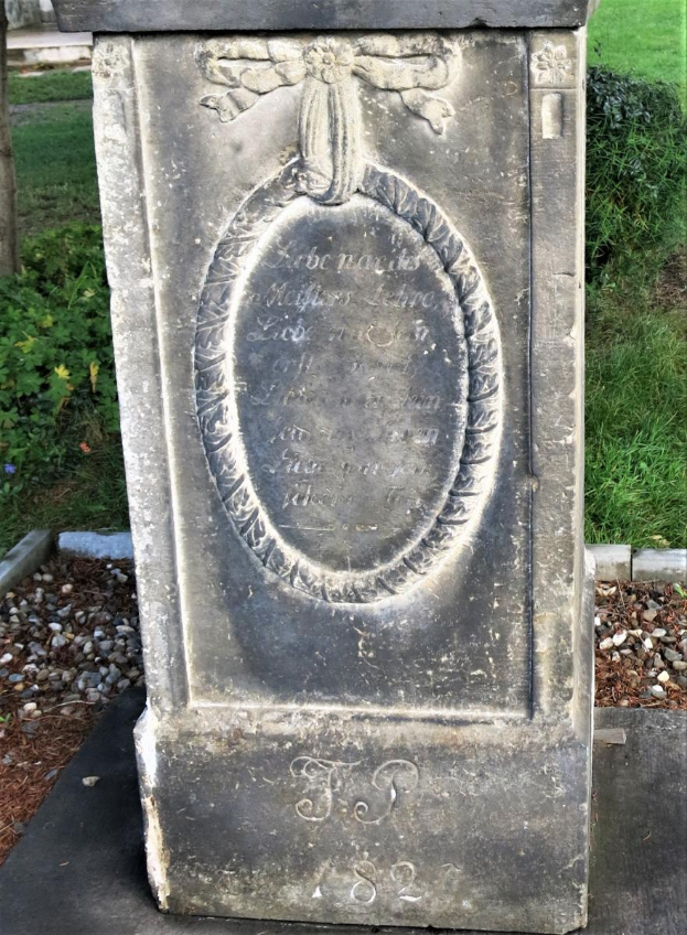 Ein steinernes Denkmal mit einer Grabplatte in einem Friedhof, umgeben von Gras und Pflanzen, mit der Inschrift "Ludwig J. Schreiber."