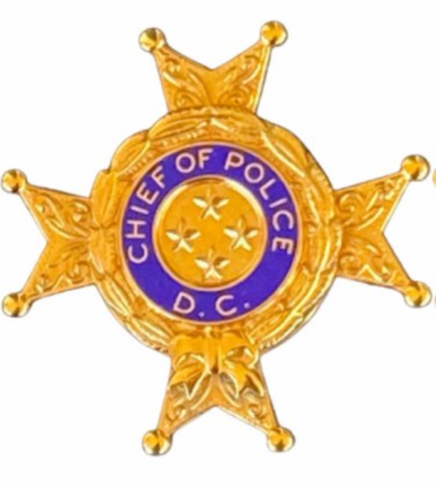 Ein Polizeiabzeichen mit der Aufschrift "Polizeipräsident" vor einem weißen Hintergrund.