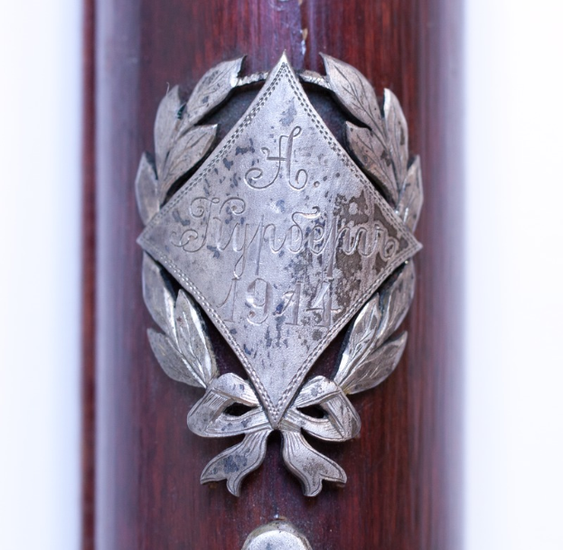 Ein Nahaufnahme eines Gewehrs mit einer Metallplakette, auf der wahrscheinlich der Name des Gewehrs eingraviert ist.