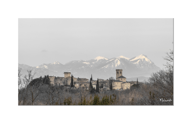 Ein Schloss in der Mitte mit Bäumen unten, Hügeln und Himmel im Hintergrund.