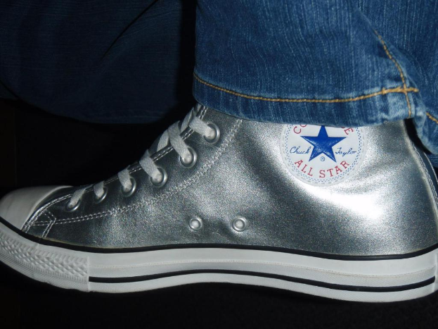 Ein Schuh mit Text und Schnürsenkeln, mit dem Rand von Jeans oben rechts im Dunkeln.
