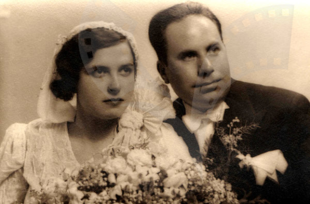 Ein Mann und eine Frau in festlicher Kleidung lächeln und posieren gemeinsam an ihrem Hochzeitstag, wobei die Frau einen Blumenstrauß hält.