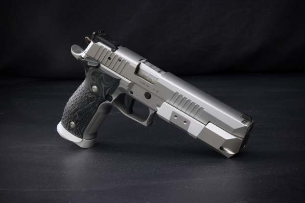 Eine Sig Sauer P226 X-Five 9mm Pistole auf einer schwarzen Oberfläche mit einem schwarzen Hintergrund.