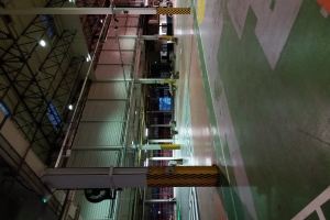 Ein großes Lager voller verschiedener Maschinen, Metallstangen, Lampen und andere Gegenstände, mit sichtbarem Text auf dem Boden rechts.